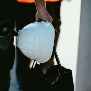 a man holding a white hard hat and a black bag
